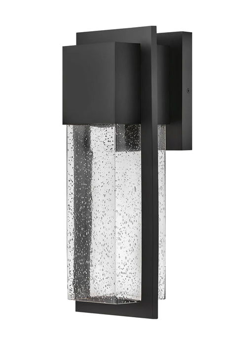 A modern outdoor wall light with a black finish and clear seeded glass featuring a rectangular design.