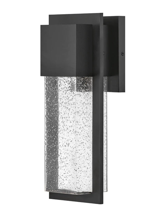 A modern outdoor wall light with a black finish and a clear glass panel.