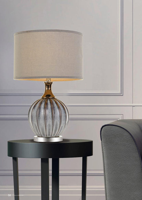 Chrome and white table lamp with a conical fabric shade, illuminated.