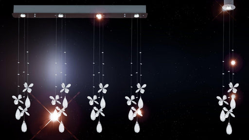 Chrome pendant light with four spherical glass shades, illuminated in a room.