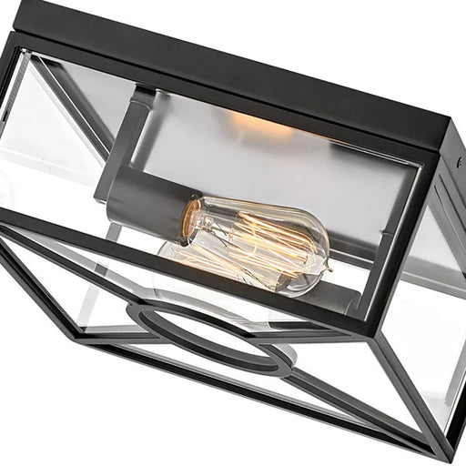 A close-up of a modern black outdoor wall light with clear glass.