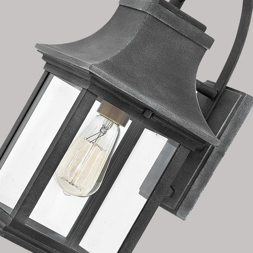 A close-up of a traditional dark bronze outdoor wall lantern with seeded glass.