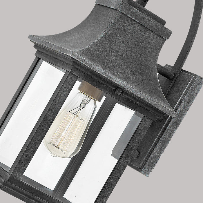 A close-up of a traditional dark bronze outdoor wall lantern with seeded glass.