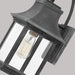 A close-up of a traditional dark bronze outdoor wall lantern with seeded glass.