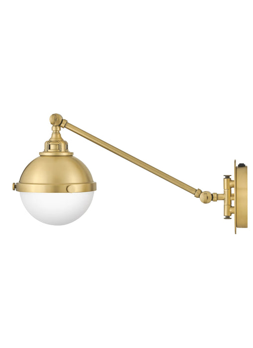 A satin brass linear pendant light with four clear glass shades viewed from a different angle.
