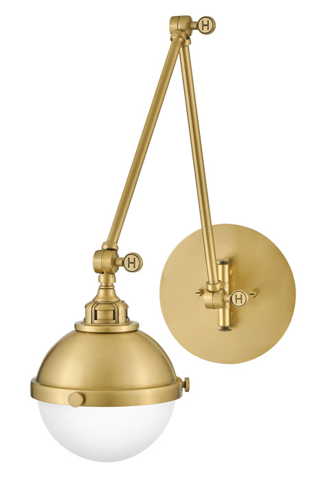 A satin brass linear pendant light with clear glass shades hanging over a kitchen island.