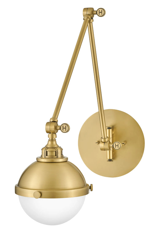 A satin brass linear pendant light with clear glass shades hanging over a kitchen island.