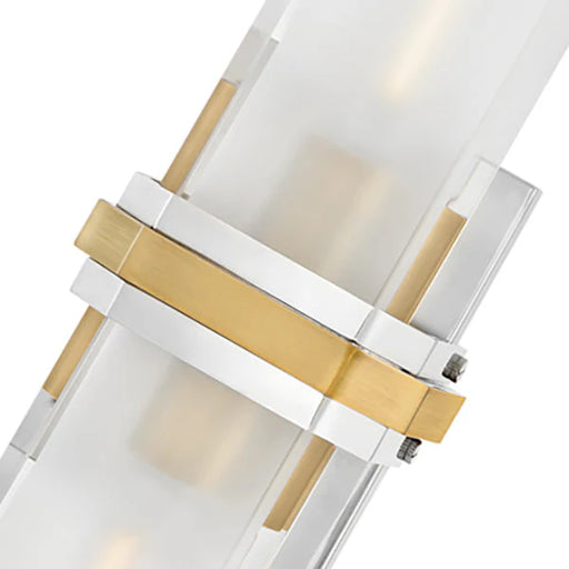 A close-up view of a modern wall sconce featuring a white cylindrical glass shade and a polished nickel base.