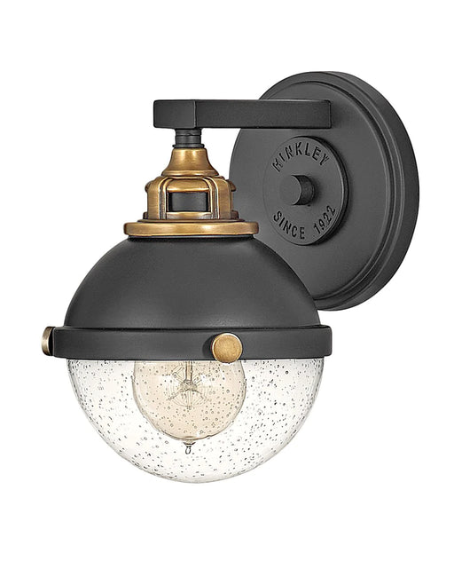 Black modern wall sconce with an elongated, cylindrical white glass shade.