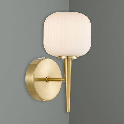 Aged gold wall sconce with a spherical opal glass shade, illuminated.