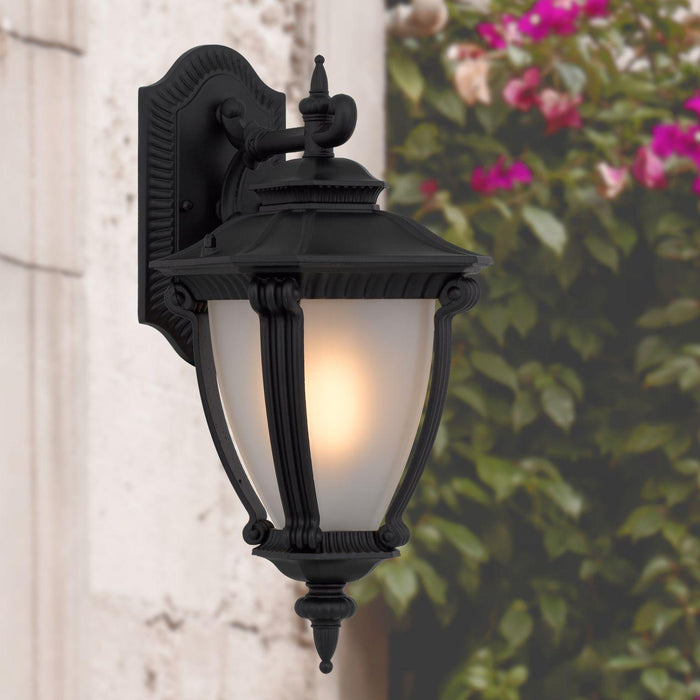 Black outdoor wall sconce with a modern, curved design, illuminated.