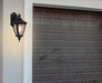 Cropped view of a black outdoor wall sconce with a modern, curved design.