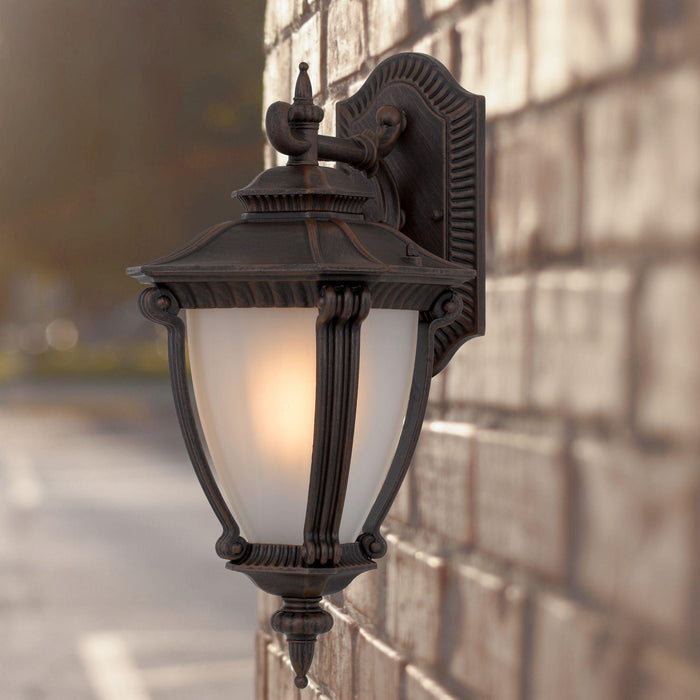Bronze outdoor wall sconce with a modern, curved design, illuminated.