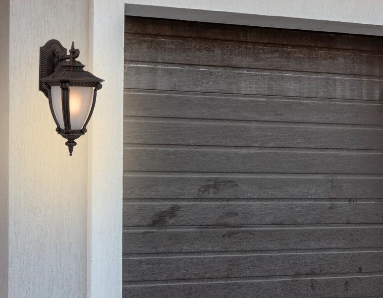Cropped view of a bronze outdoor wall sconce with a modern, curved design.