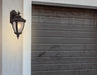 Cropped view of a bronze outdoor wall sconce with a modern, curved design.