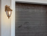 Cropped view of a gold outdoor wall sconce with a modern, curved design.