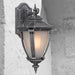 Silver outdoor wall sconce with a modern, curved design, illuminated.