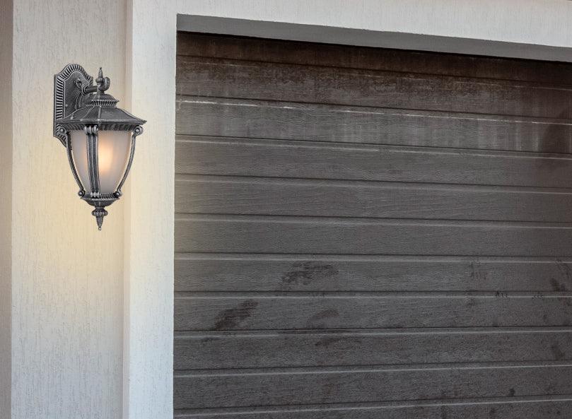Cropped view of a silver outdoor wall sconce with a modern, curved design.