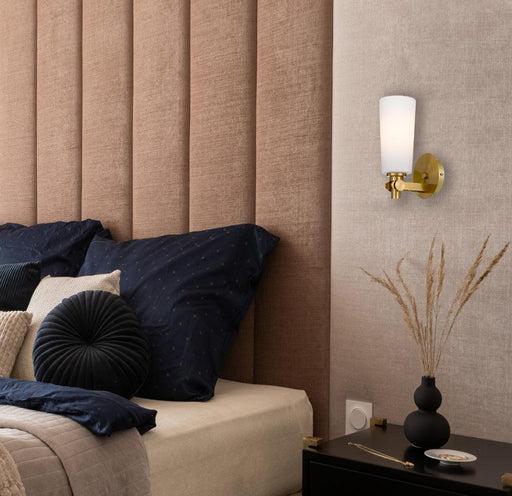 Cropped view of an aged gold outdoor wall sconce with an opal glass panel.