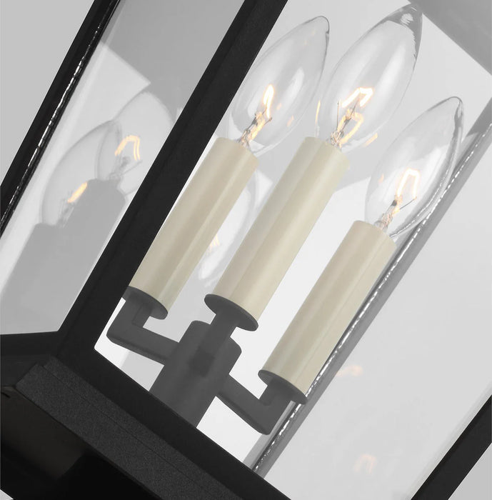 A close-up of a modern textured black outdoor wall light with seeded glass.
