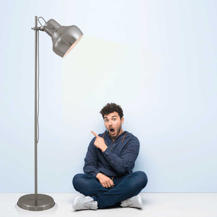 Nickel floor lamp with a cylindrical fabric shade, illuminated.