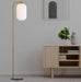 Aged gold floor lamp with an opal glass shade, illuminated.