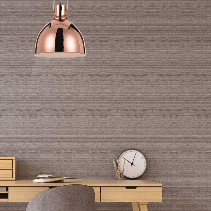 Copper pendant light with a clear glass diffuser, illuminated.
