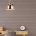 Copper pendant light with a clear glass diffuser, illuminated.