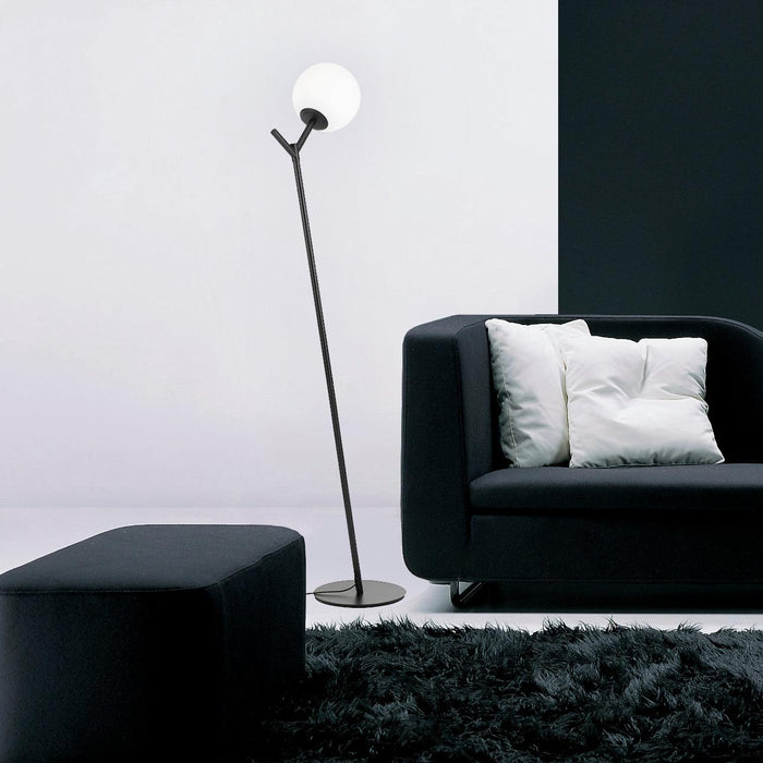 Black floor lamp with an opal glass shade, cropped view.