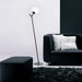 Black floor lamp with an opal glass shade, cropped view.