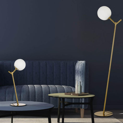 Aged gold floor lamp with an opal glass shade, illuminated.