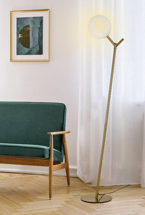 Aged gold floor lamp with an opal glass shade, cropped view.