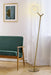 Aged gold floor lamp with an opal glass shade, cropped view.