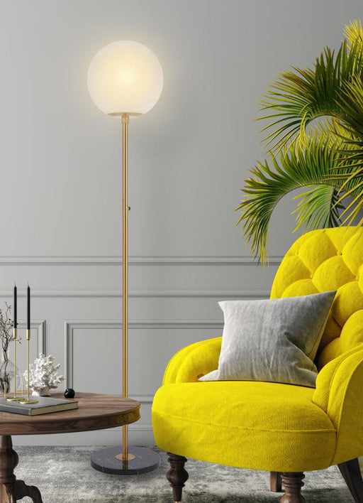 Aged gold floor lamp with a marble base and a spherical glass shade, cropped view.