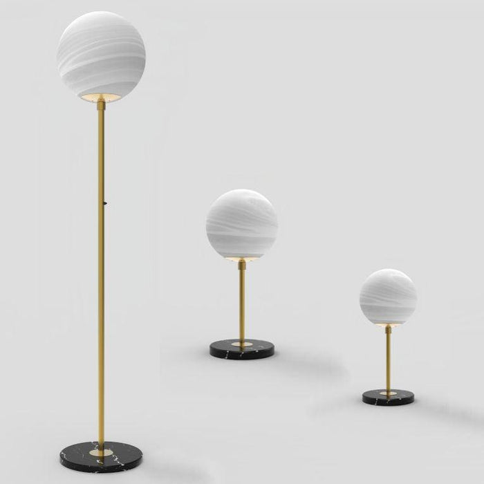 Aged gold floor lamp with a marble base and a spherical glass shade, with a matching table lamp.