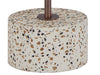 Close-up of the white terrazzo and bronze base of a floor lamp.