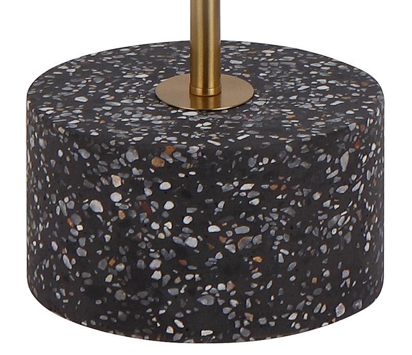 Close-up of the black terrazzo and aged gold base of a floor lamp.