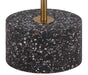 Close-up of the black terrazzo and aged gold base of a floor lamp.