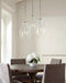 Chrome pendant light with a clear bell-shaped glass shade, in a room setting.