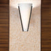Black outdoor wall sconce with a rectangular shape and a clear glass panel, illuminated.