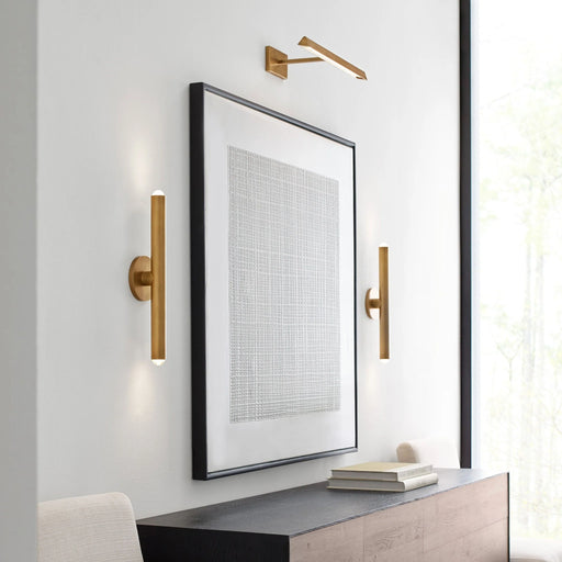 A modern cylindrical wall sconce with a bronze finish installed on an outdoor wall.