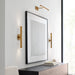 A modern cylindrical wall sconce with a bronze finish installed on an outdoor wall.