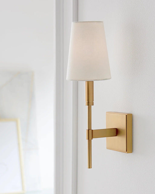 Distressed black wall sconce with a cylindrical light source, in a classic setting.